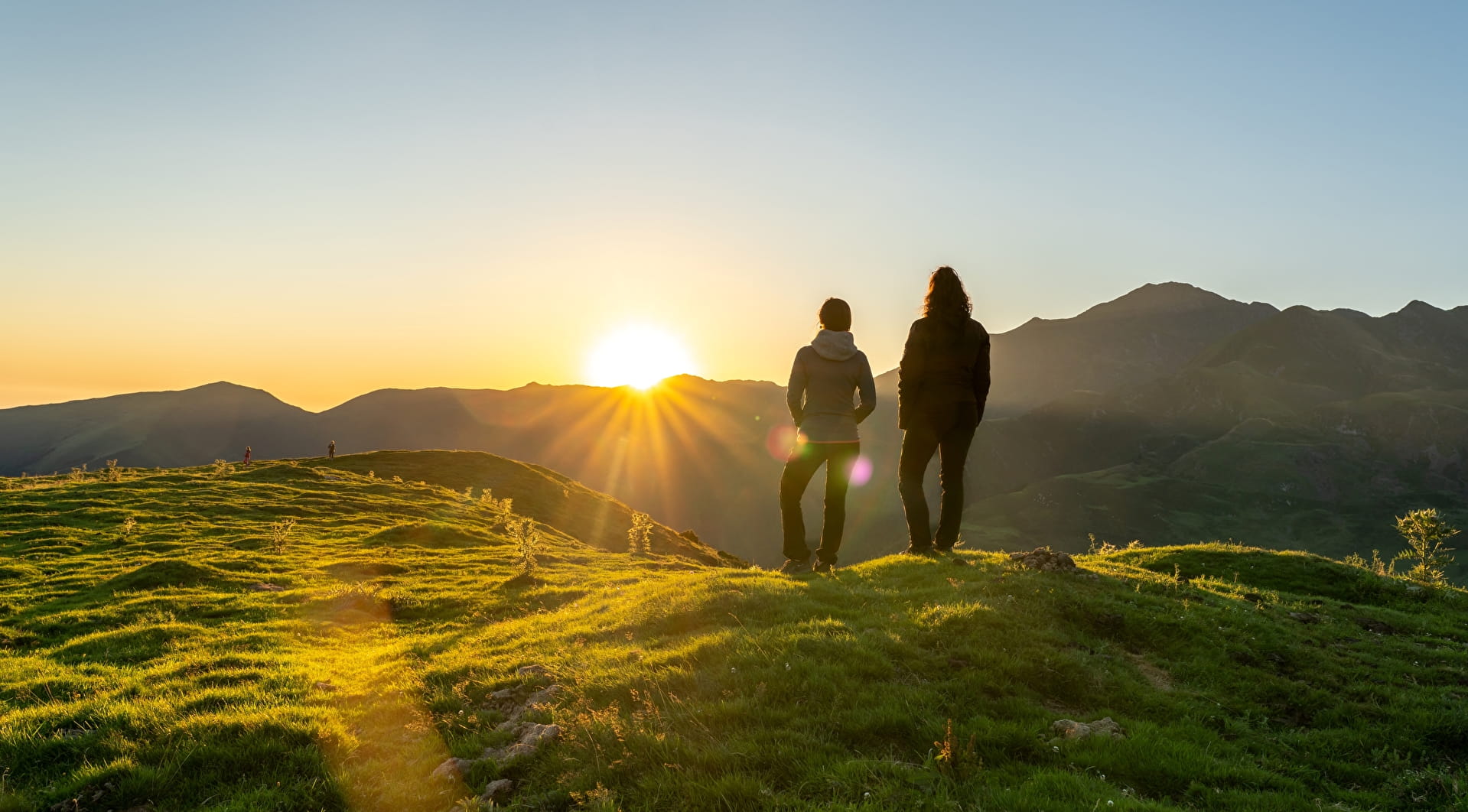 Deux personnes face à un lever de soleil en montagne